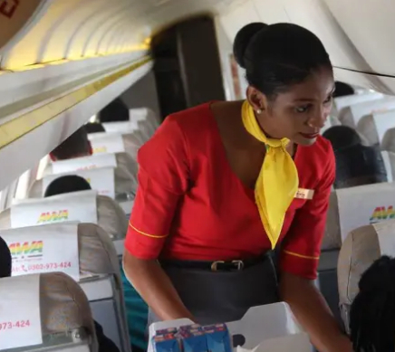 Africa World Airlines cabin crew female serving refreshing meal on-board an Africa World Airlines flight.
